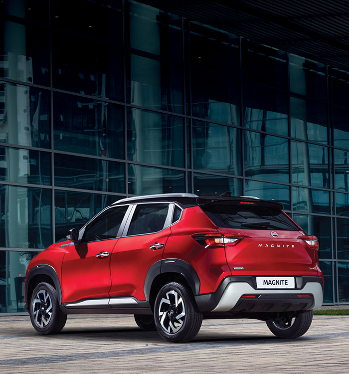 Red Nissan Magnite rear view in front of building